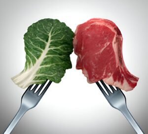 Visual comparison of plant-based leafy greens and meat on forks, highlighting the choice between plant-based and animal-based diets.