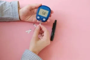 Checking normal blood sugar levels with a finger-prick glucose meter showing 5.8 mmol/L