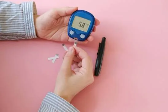 Checking normal blood sugar levels with a finger-prick glucose meter showing 5.8 mmol/L